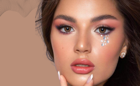 Close-up of a person with makeup and jewelry on a beige background
